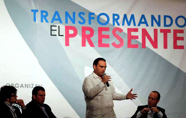 Foto del Gobernador de Quinatana Roo, Roberto Angulo en la presentacion de la Cumbre Iberoamericana. Nuestro trabajo al fondo de la imagen.